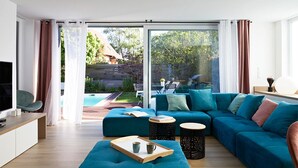 A modern living room with a teal sofa, a wooden coffee table, and a TV on a white cabinet. - Chic and Cosy in Alsace (Hindisheim)