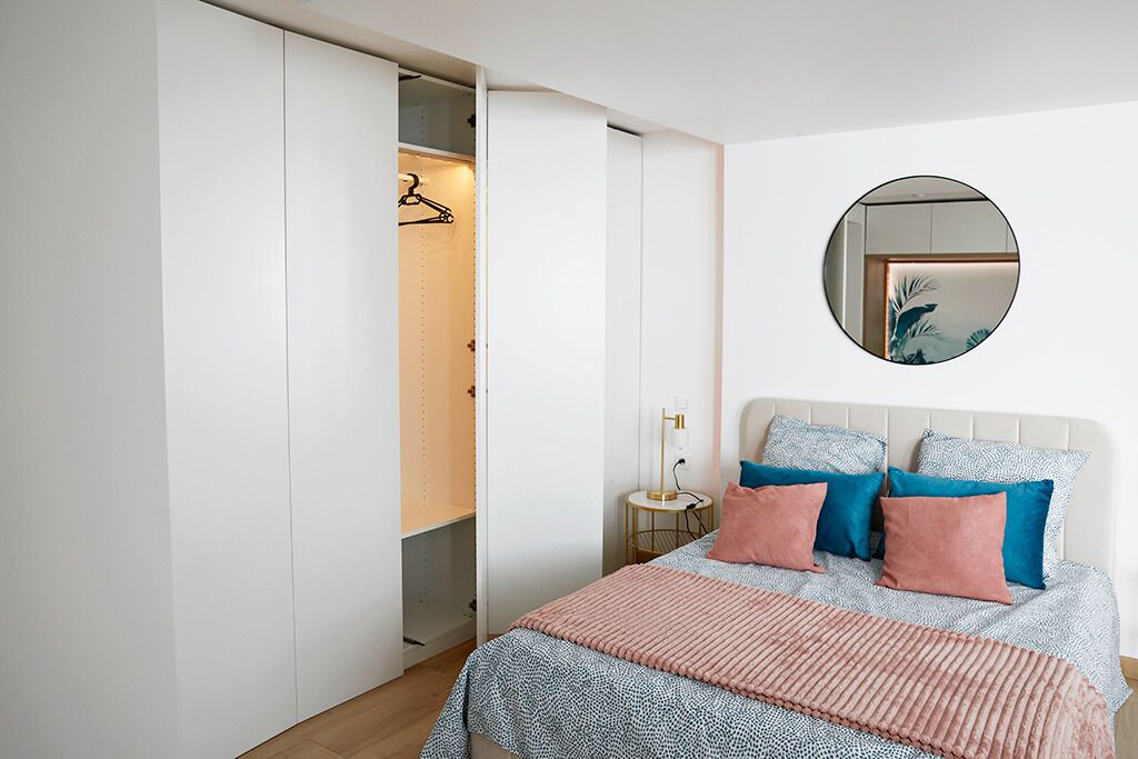 A bedroom with a bed, bedside table, and a wardrobe.