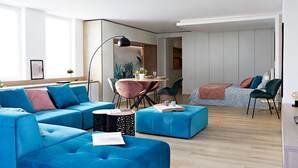 A modern living room with blue sofas, a dining table with chairs, and a kitchen area in the background. - Chic and Cosy in Alsace (Hindisheim)