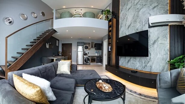 A modern living room with a grey sofa, a round coffee table, and a staircase leading to an upper level. - EBS LEGEND GHANA  (Accra)