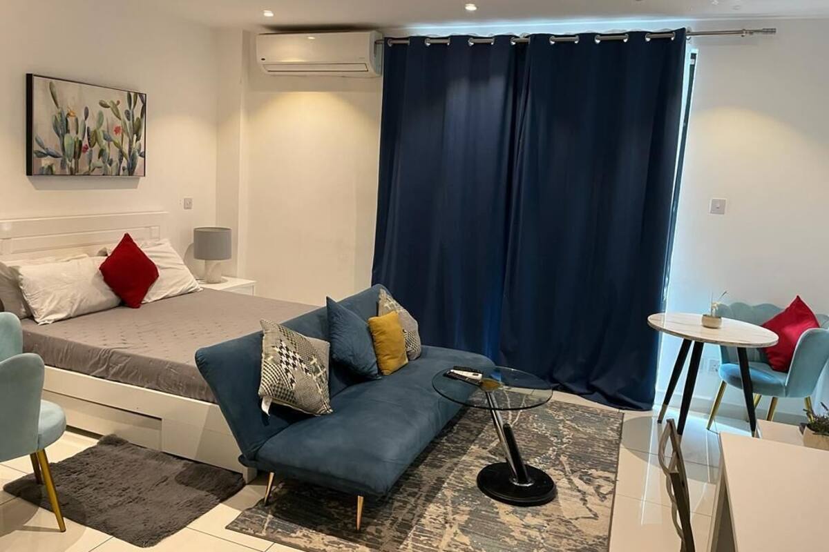 A modern bedroom with a bed, a blue sofa, a small round table, and a chair.