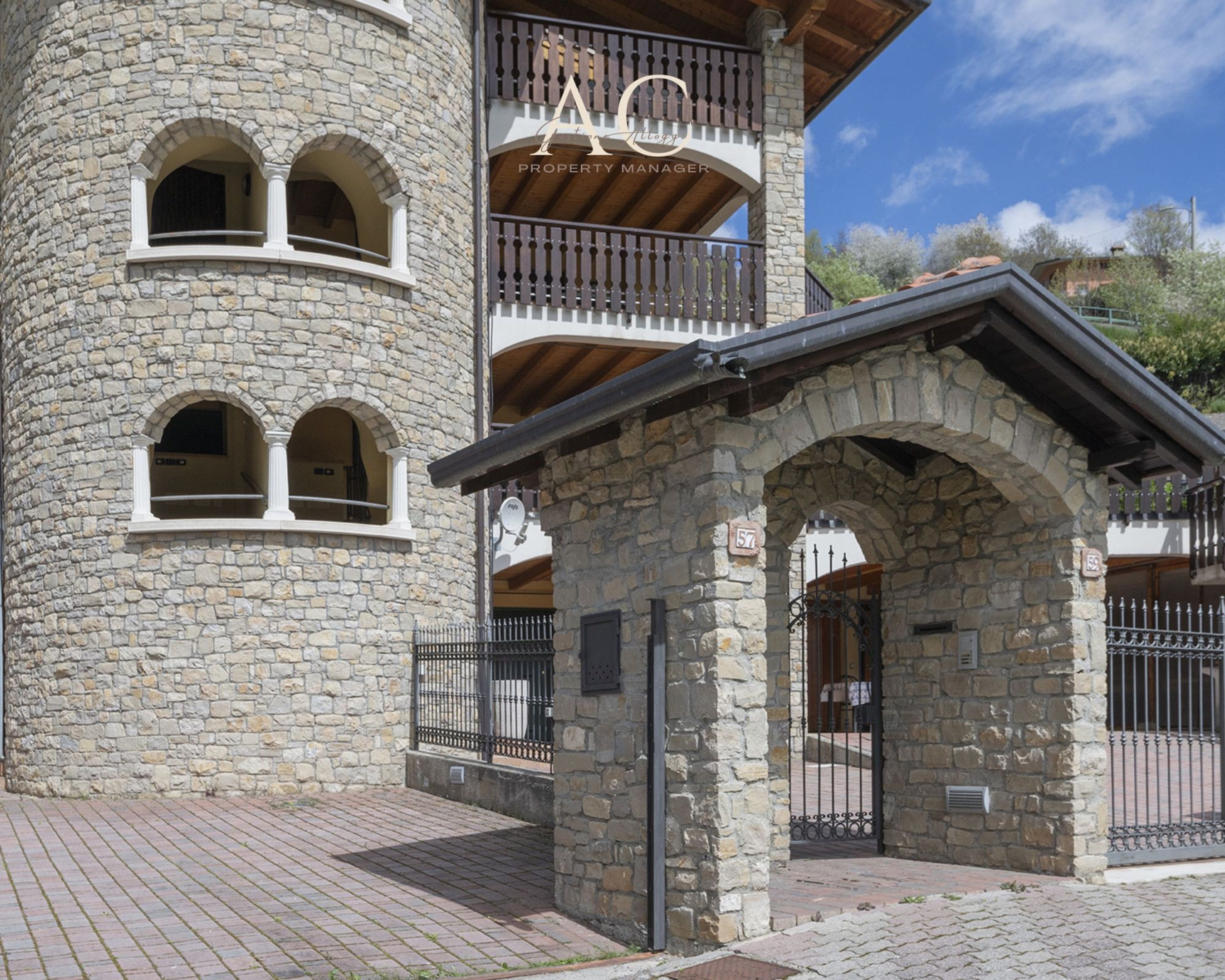 A stone building with balconies, a gated entrance, and a sign reading 'PROPERTY MANAGER'.