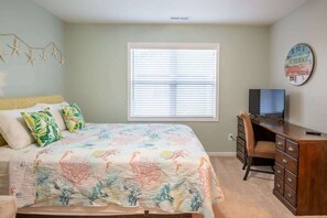 Ein Schlafzimmer mit Bett, Schreibtisch und Fenster.
