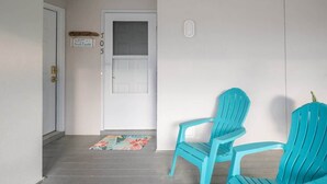 A porch with two turquoise Adirondack chairs, a white door, and a welcome sign. - Marsh Girl Suite: St. James Studio - Beach Club, Pool & Marina (Southport)