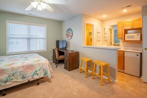 Un dormitorio con cama, escritorio y kitchenette.