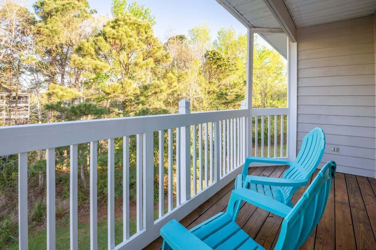 A covered porch with white railings and blue Adirondack chairs.