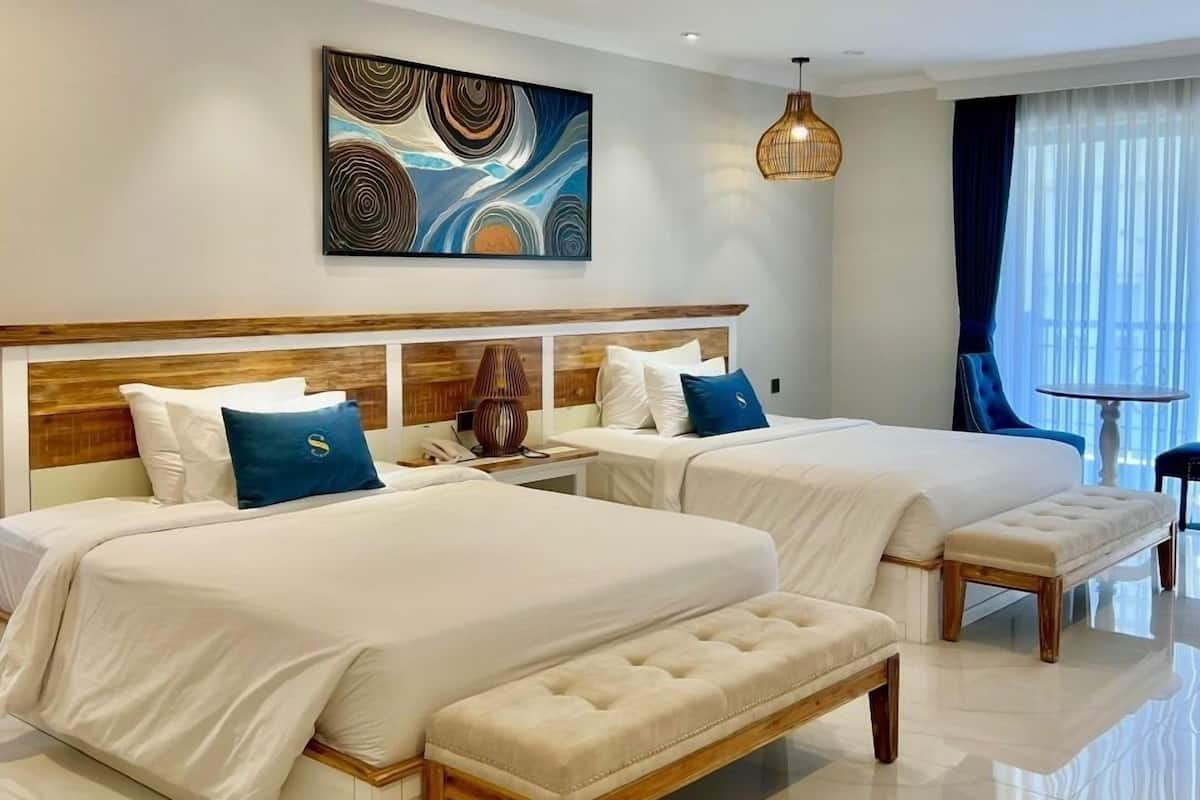 Ein modernes Hotelzimmer mit zwei Betten, einem großen abstrakten Gemälde, einem hölzernen Kopfteil und Blick ins Freie.