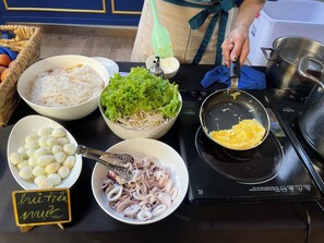 A kitchen counter with various food items including noodles, lettuce, eggs, and octopus. - Sabina Luxury Boutique Hotel & Villa (Ho Chi Minh City)
