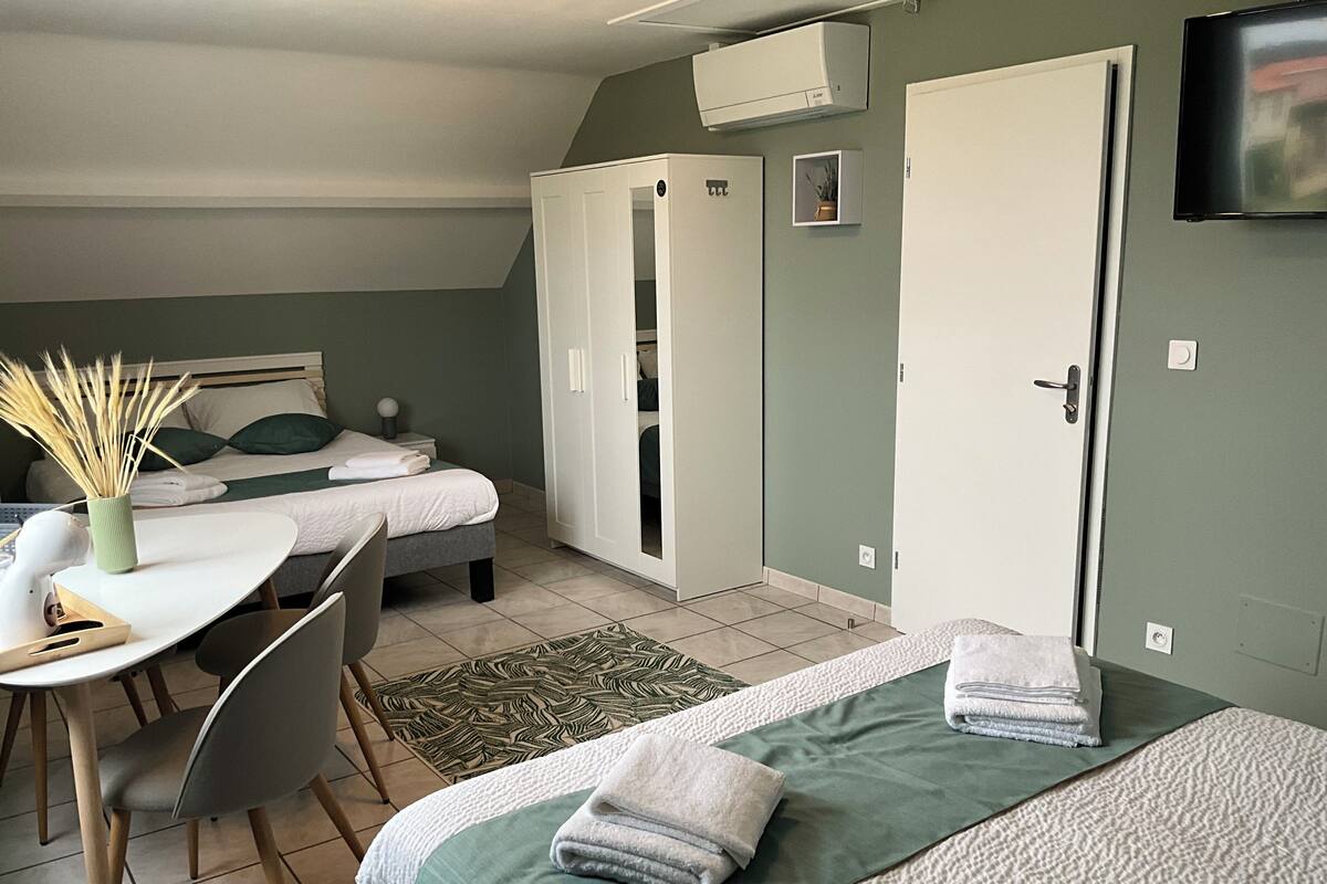Ein Hotelzimmer mit zwei Betten, einem Schreibtisch, einem Sessel, einem Fernseher und einem Kleiderschrank.