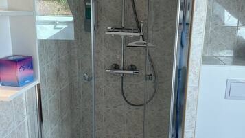 Een moderne badkamer met een douchecabine van glas, een toilet en een wastafel.