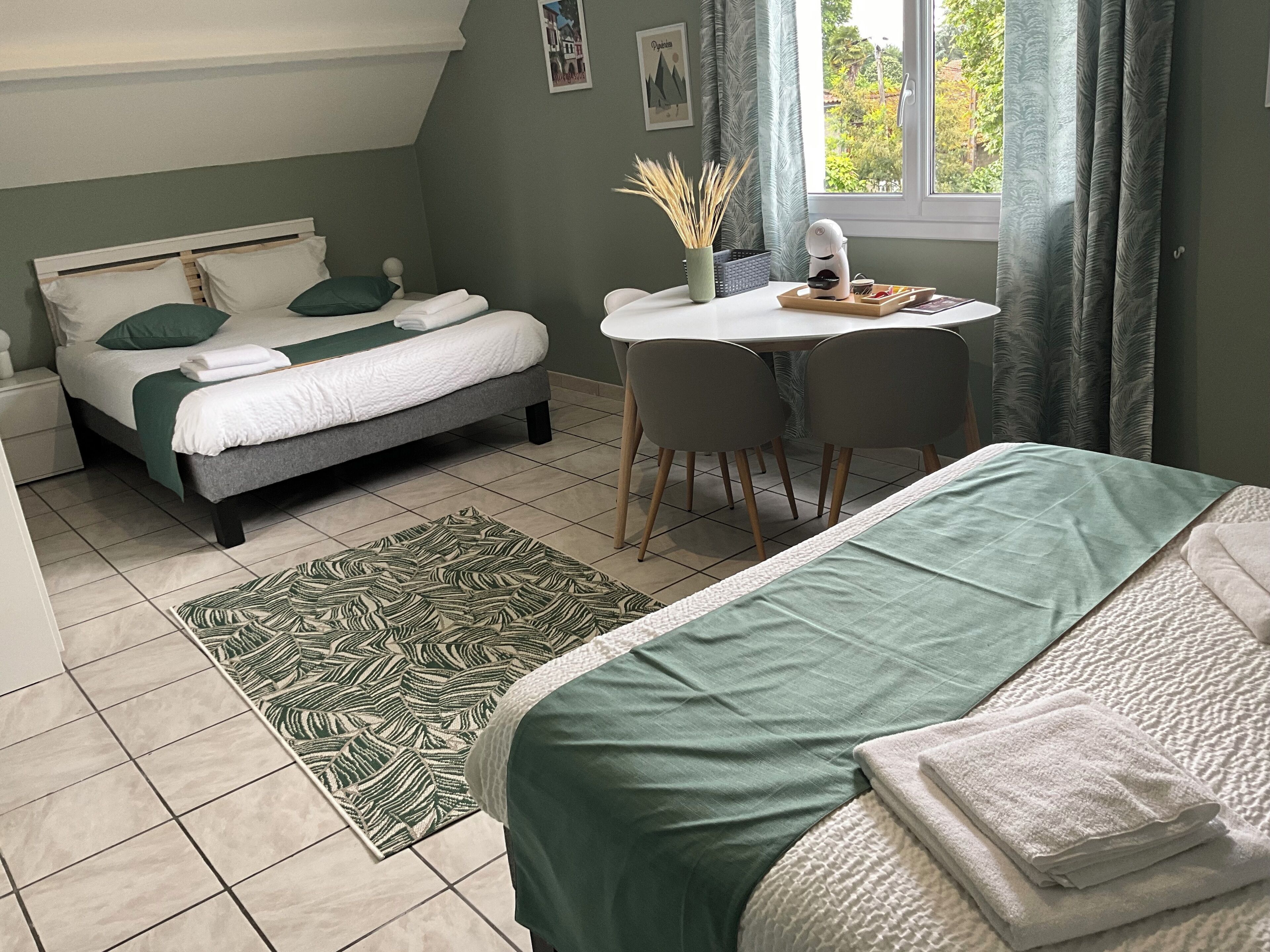 Un dormitorio con cama, escritorio y silla. Hay una ventana con cortinas y vistas a árboles.