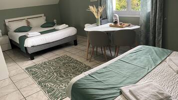 Un dormitorio con cama, escritorio y silla. Hay una ventana con cortinas y vistas a árboles.