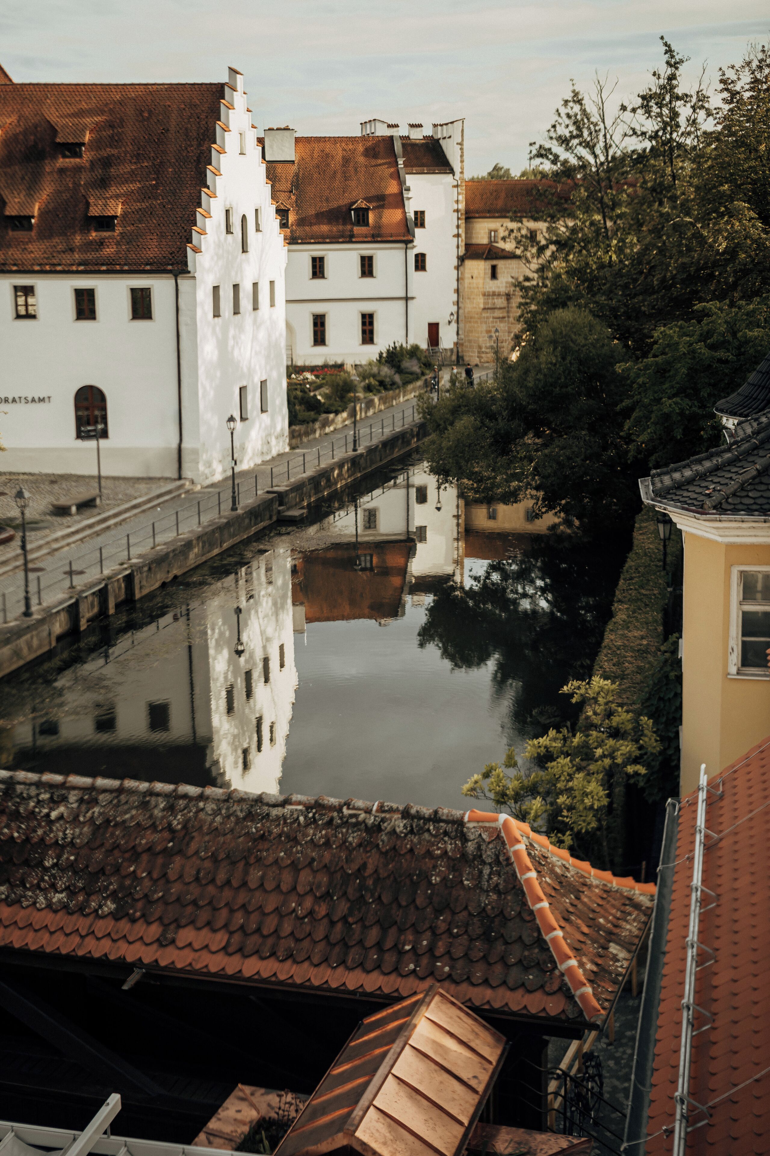 Ein Kanal mit Gebäuden, die sich im Wasser spiegeln, eine Brücke und ein Gebäude mit weißer Fassade.