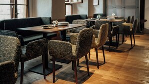 A modern restaurant with dark upholstered seating, wooden tables, and a polished floor. - Bootshaus Amberg  (Amberg)