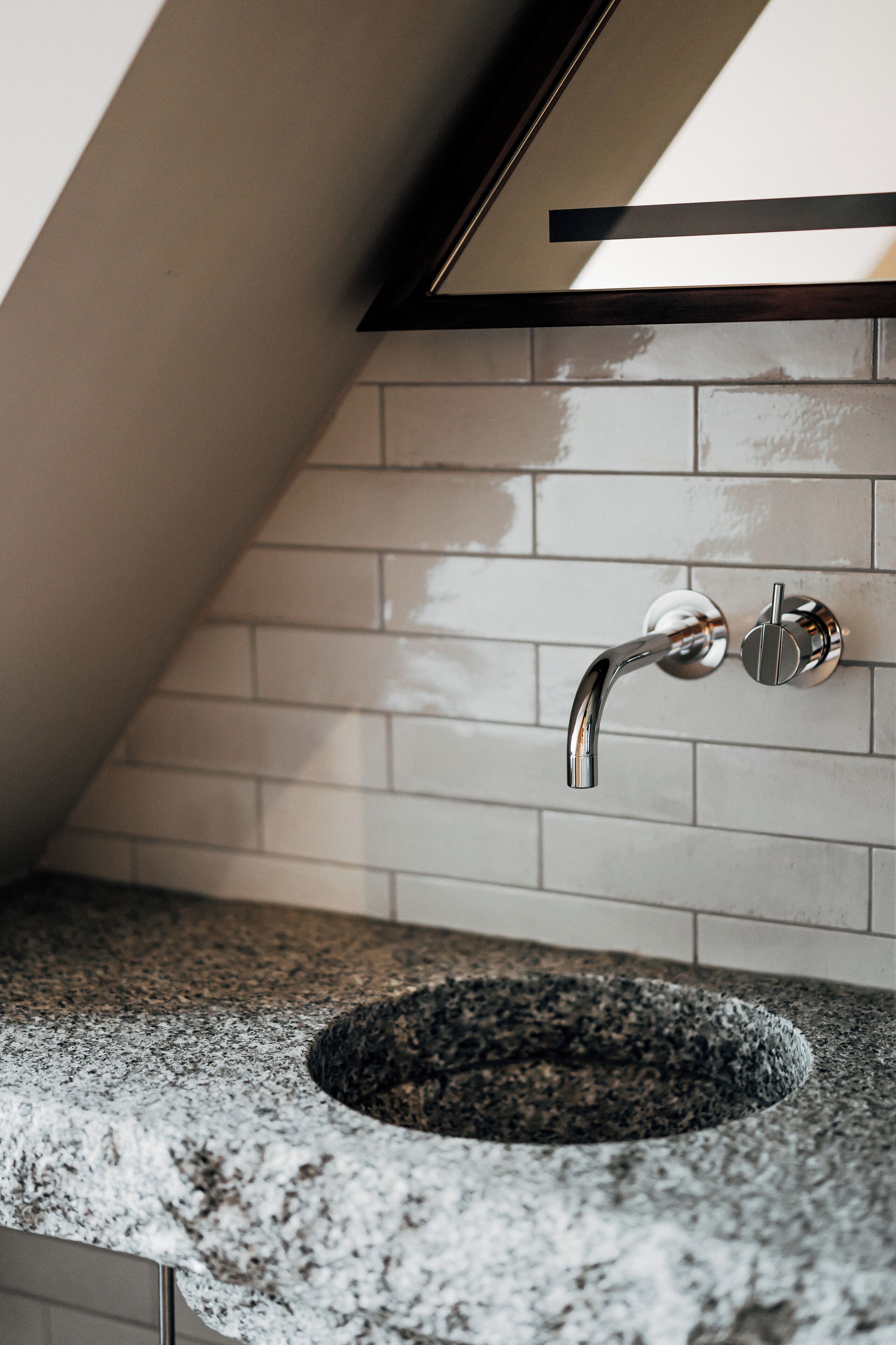 Un baño con encimera de granito, un lavamanos con grifo cromado y pared con azulejos.