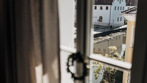 A view through a window with a curtain, revealing a building with a white facade and a reflection in the water below. - Bootshaus Amberg  (Amberg)