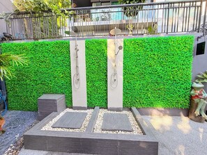 A modern outdoor shower area with a green wall backdrop, two shower heads, and a pebble-patterned floor. - B305 - 1 Bedroom Serviced Apartment Pool View near Ao Nang Beach (Tambon Ao Nang)