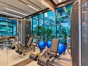 A gym with exercise equipment, large windows, and a view of a building outside.