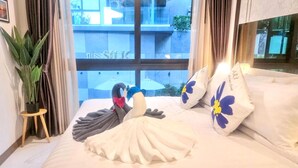 A hotel room with a bed, a potted plant, and a view of a building outside. - B305 - 1 Bedroom Serviced Apartment Pool View near Ao Nang Beach (Tambon Ao Nang)