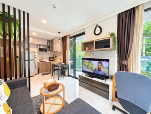 A modern living room with a television, a dining area, and a kitchen.