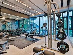 A modern gym with various exercise equipment, large windows, and a view of the outdoors. - B305 - 1 Bedroom Serviced Apartment Pool View near Ao Nang Beach (Tambon Ao Nang)