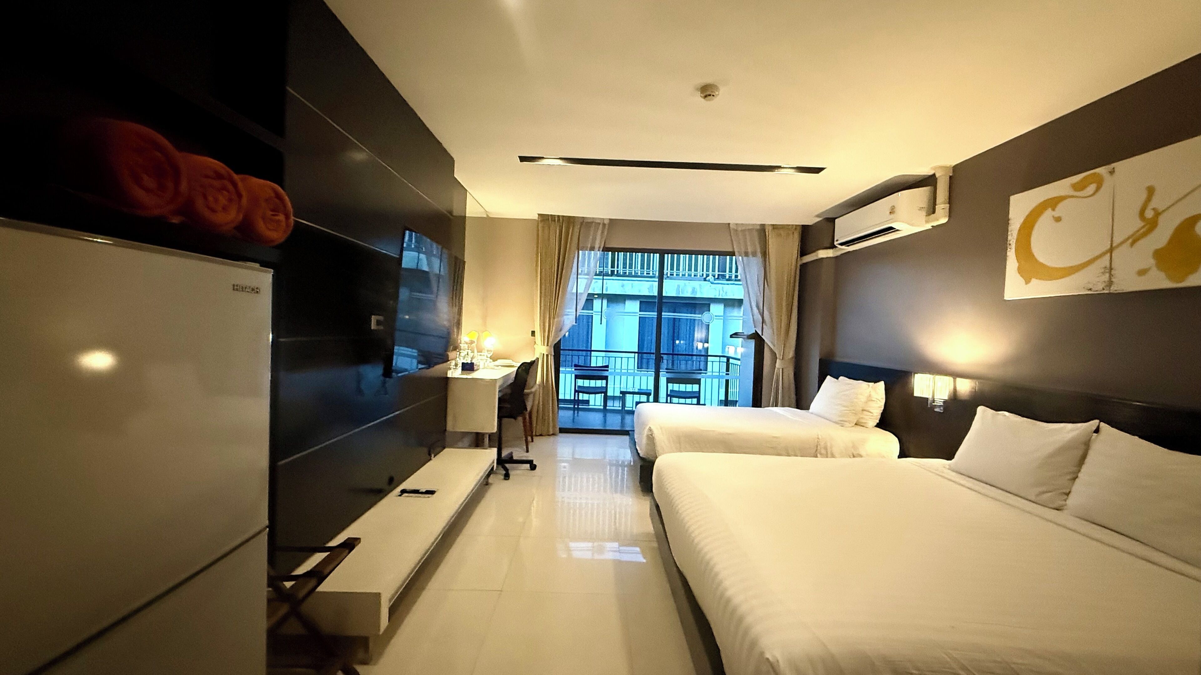 Een hotelkamer met een bed, een bureau, een televisie en uitzicht op de stad.