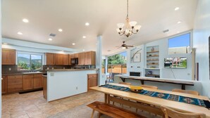 A spacious kitchen with wooden cabinets, a central island, and a dining area with a long table and benches.