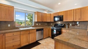 A modern kitchen with wooden cabinets, granite countertops, a dishwasher, a stove, and a microwave.