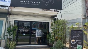 Un escaparate con un cartel para el café 'Black Turtle', presentando una exposición fotográfica de Edmund Tair.