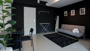 Una sala de estar moderna con un sofá gris, un tapete blanco y negro estampado, una puerta blanca y un espejo con marco negro.