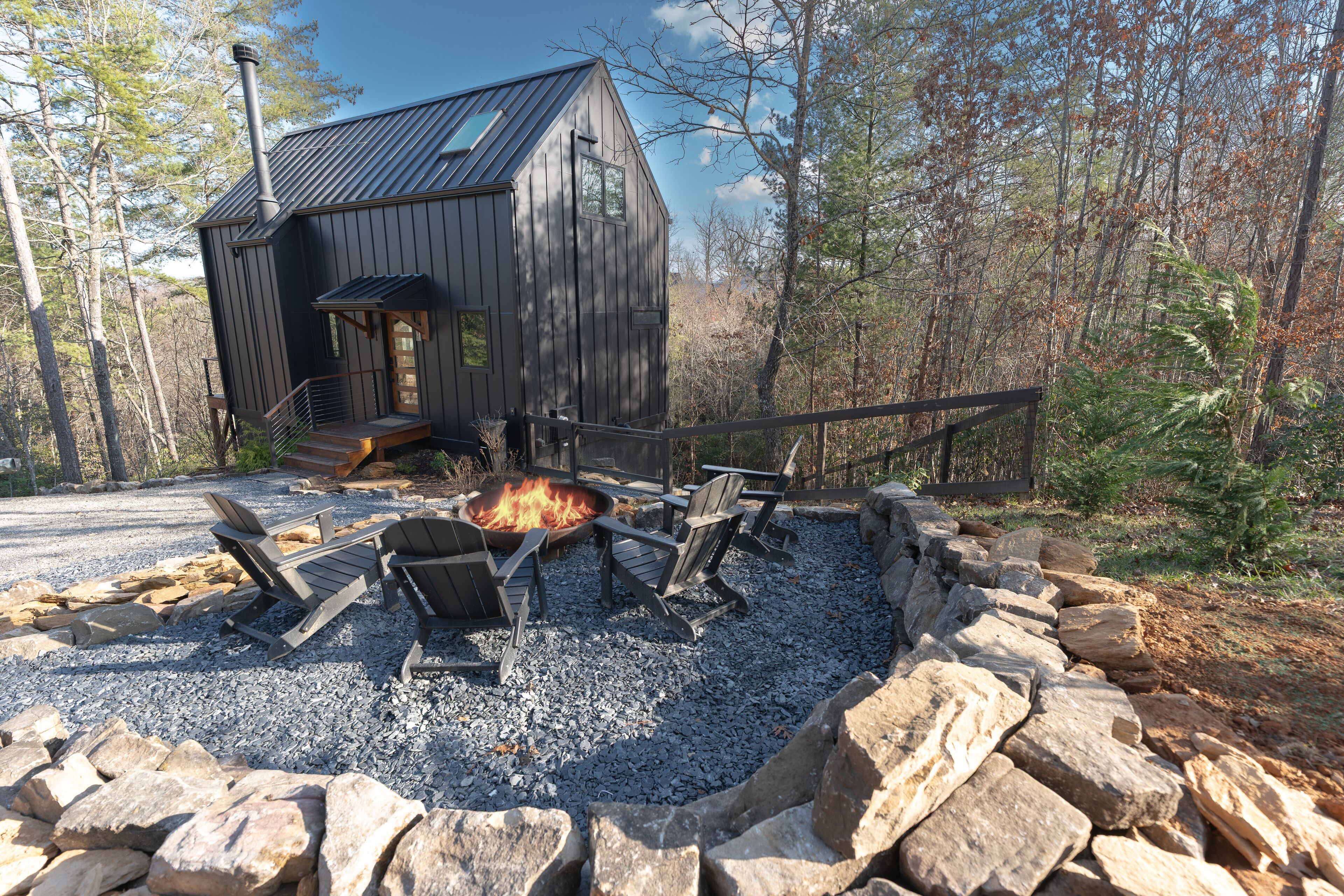 Modern mountain cabin with a private fire pit, Adirondack seating, and peaceful forest views. An ideal nature getaway.
