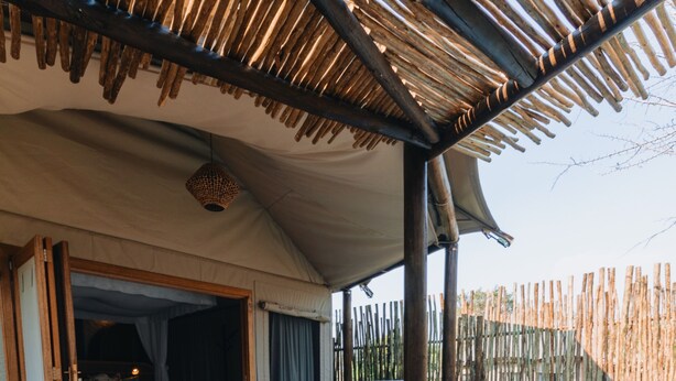 Un espacio exterior acogedor con piscina, banca de madera y zona de descanso cubierta.