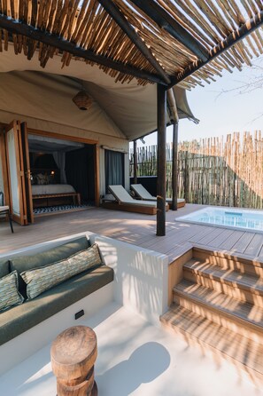 Un espace extérieur accueillant avec une piscine, un banc en bois et un coin abrité pour se reposer.