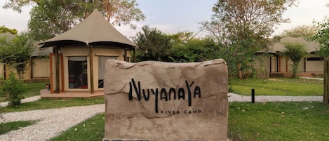 A sign for Nuyanya River Camp with a building in the background.