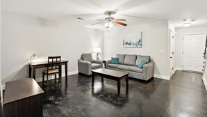 A living room with a ceiling fan, a sofa, a coffee table, a desk, and a chair.