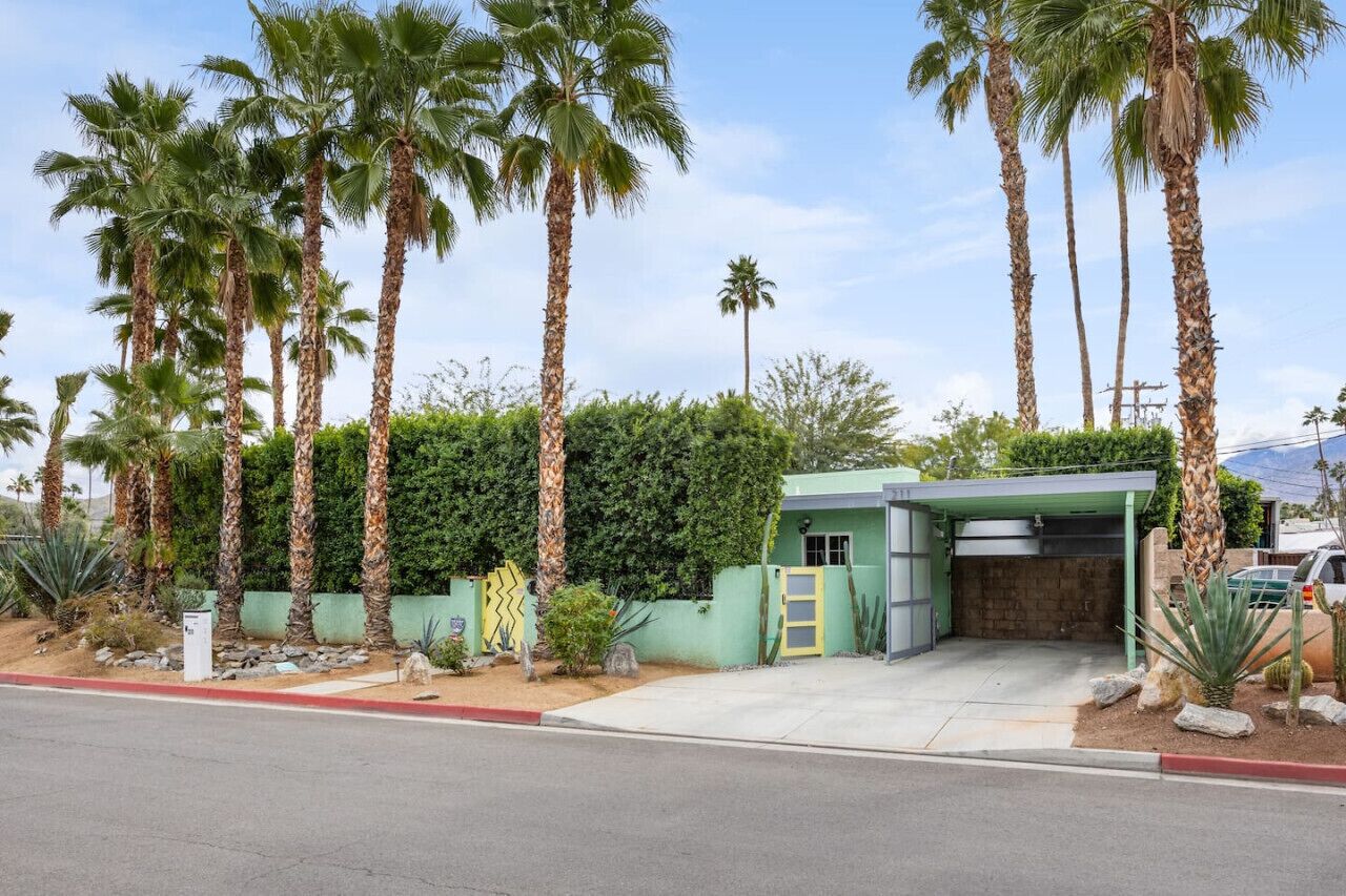 A single-story building with a green exterior, a garage, and a small patio area.