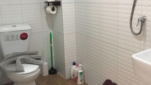 A bathroom with a toilet, a shower, and a pair of slippers. - 3 Bedroom Villa Din Daeng BKK (Bangkok)