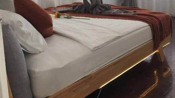 A modern bedroom with a wooden bed frame, grey curtains, and a white mattress. - 3 Bedroom Villa Din Daeng BKK (Bangkok)