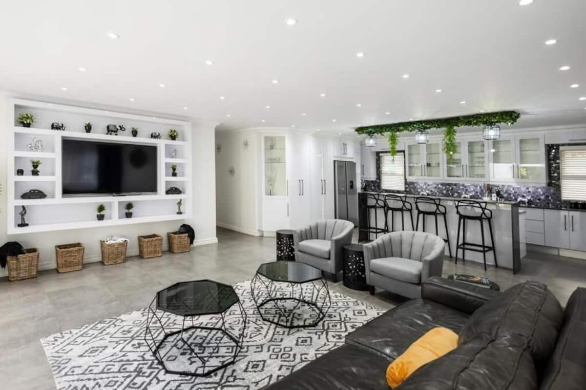 Una sala de estar moderna con un televisor grande, asientos cómodos, una zona de cocina y un comedor.