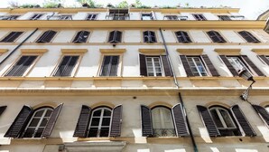 A multi-story building with arched windows and shutters, featuring a consistent architectural style. - Louly Trevi Fountain 4 Bedroom Luxury Apartment (Roma)