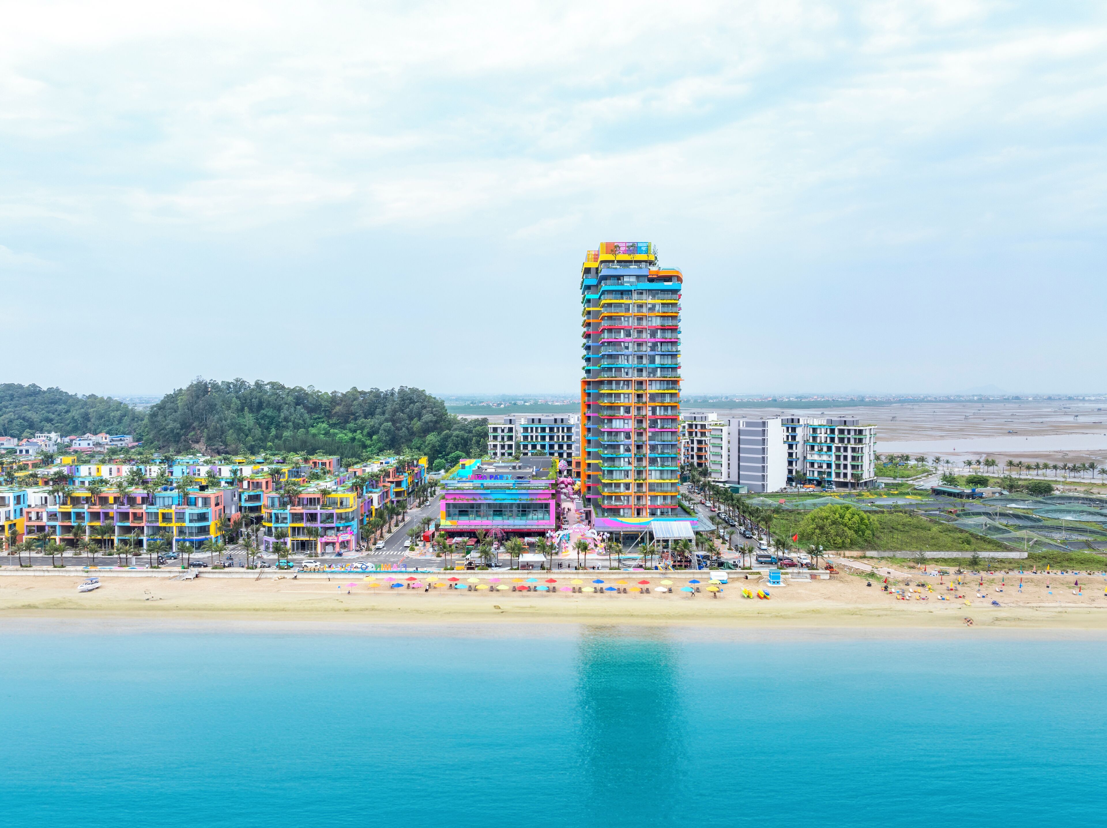 Un grand hôtel aux couleurs vives, avec vue sur la plage.