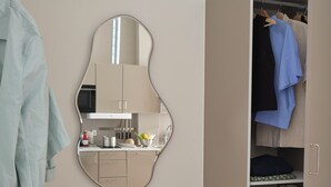 Una habitación con armario, espejo y kitchenette.