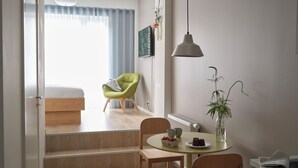 Una habitación moderna y bien iluminada con comedor, una silla verde, una mesa con frutero y un radiador.
