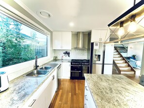 Una cocina moderna con armarios blancos, un lavamanos de acero inoxidable, horno empotrado y refrigerador.