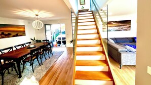 Ein modernes Interieur mit einer Holztreppe, einem Essbereich und einem Wohnzimmer.