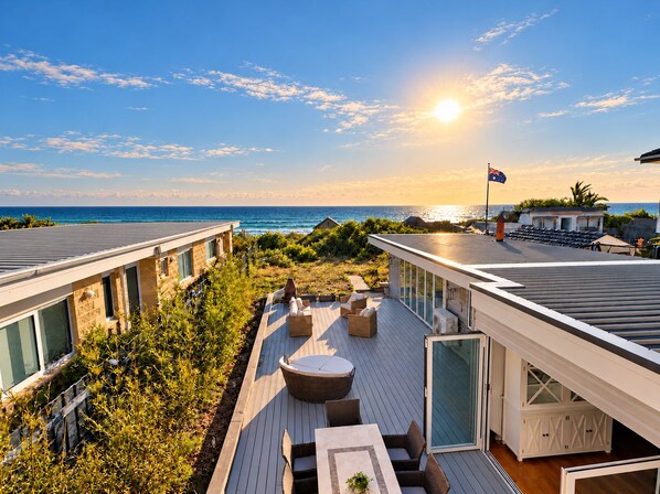 Un moderno resort con una terraza con vistas al océano, que ofrece asientos al aire libre y una bandera.
