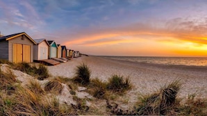 Ein Strand mit einer Reihe von Strandkörben und einem Sonnenuntergang.