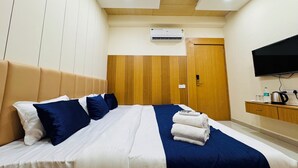 A hotel room with a bed, a TV, an air conditioning unit, and a wooden wardrobe. - Hotel Shivlok (Ujjain)