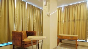 A room with a sofa, a small round table, and a wooden desk. - Hotel Shivlok (Ujjain)