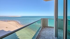 A balcony with a glass railing overlooking a beach and the ocean. - Ocean Wrap Around Oceanfront Balcony at Tessoro (Las Conchas)